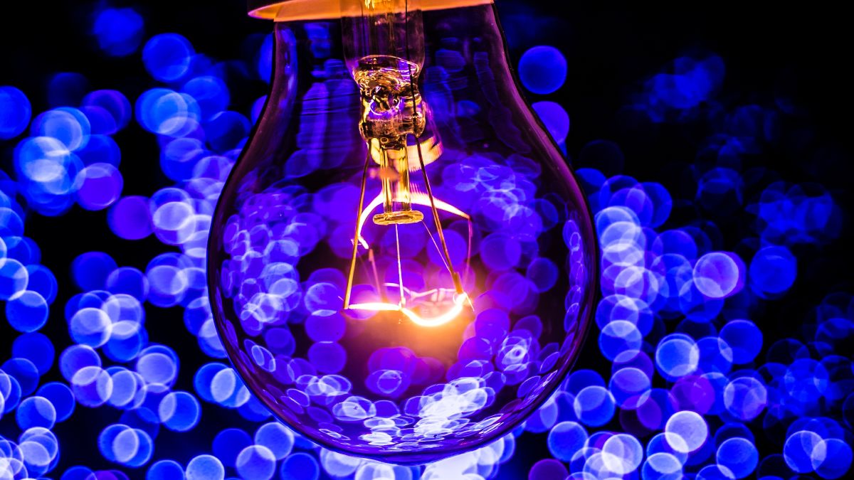 Bombilla de luz encendida sobre fondo azul