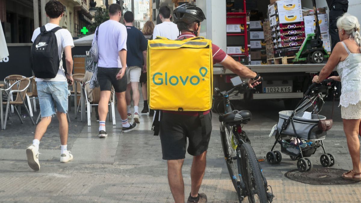 Un repartidor de Glovo arrastrando una bicicleta