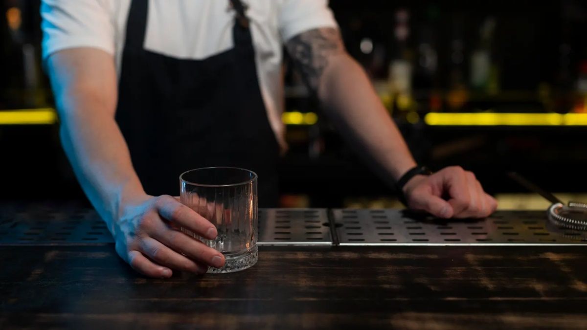 un camarero preparando una bebida en una barra de bar