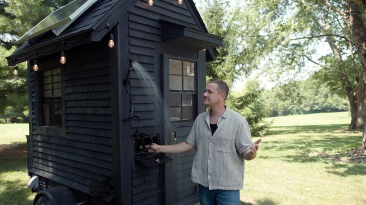 El creador con su minicasa probando la ducha