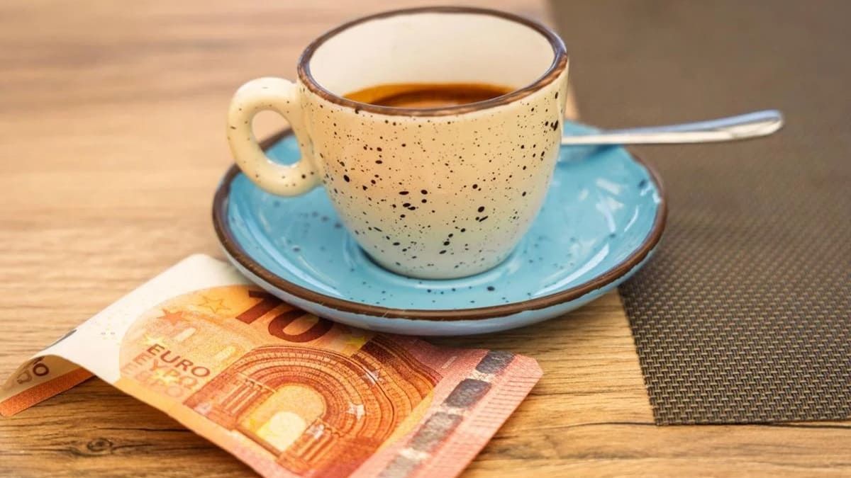 Una taza de café junto a un billete de diez euros