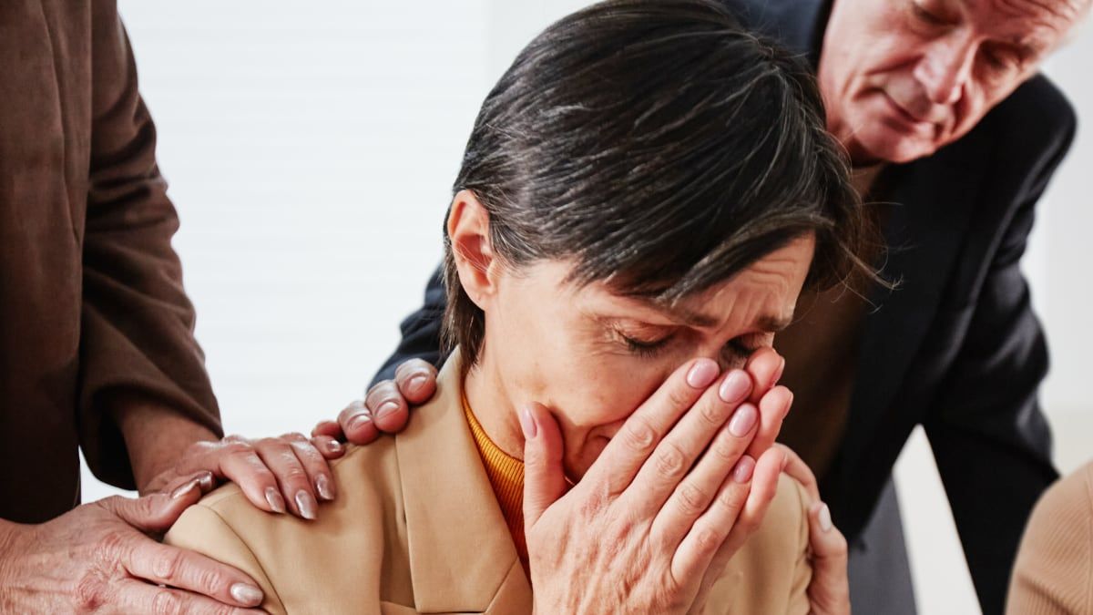 Una mujer llorando con personas al lado