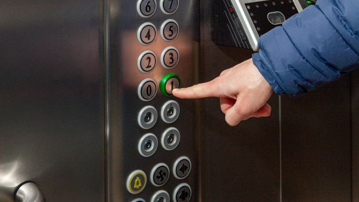 Una persona presionando los botones de un ascensor