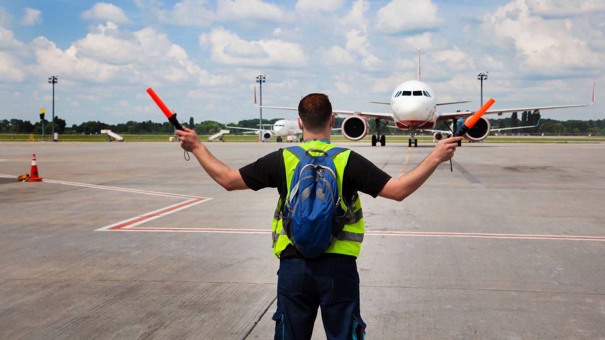 Un trabajador de aeropuerto realizando señales en pista