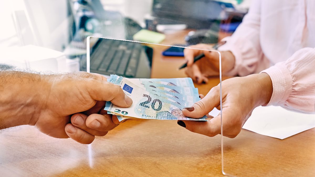 Persona sacando dinero en la ventanilla de un banco 