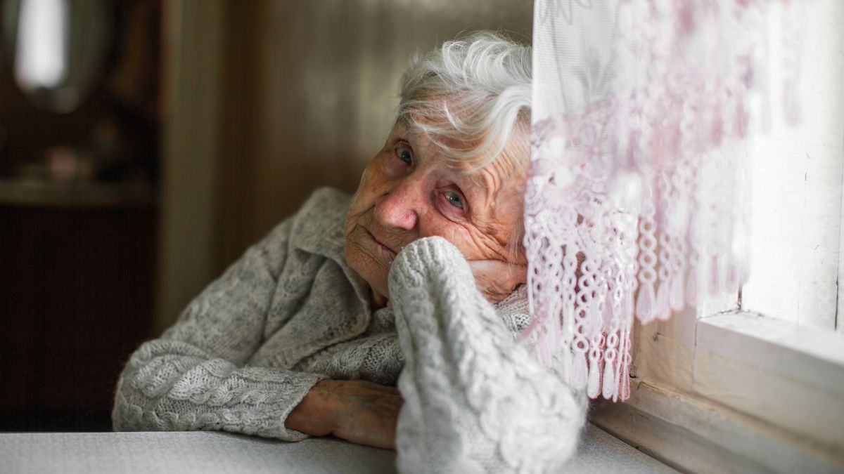 Anciana llorando mirando por la ventana