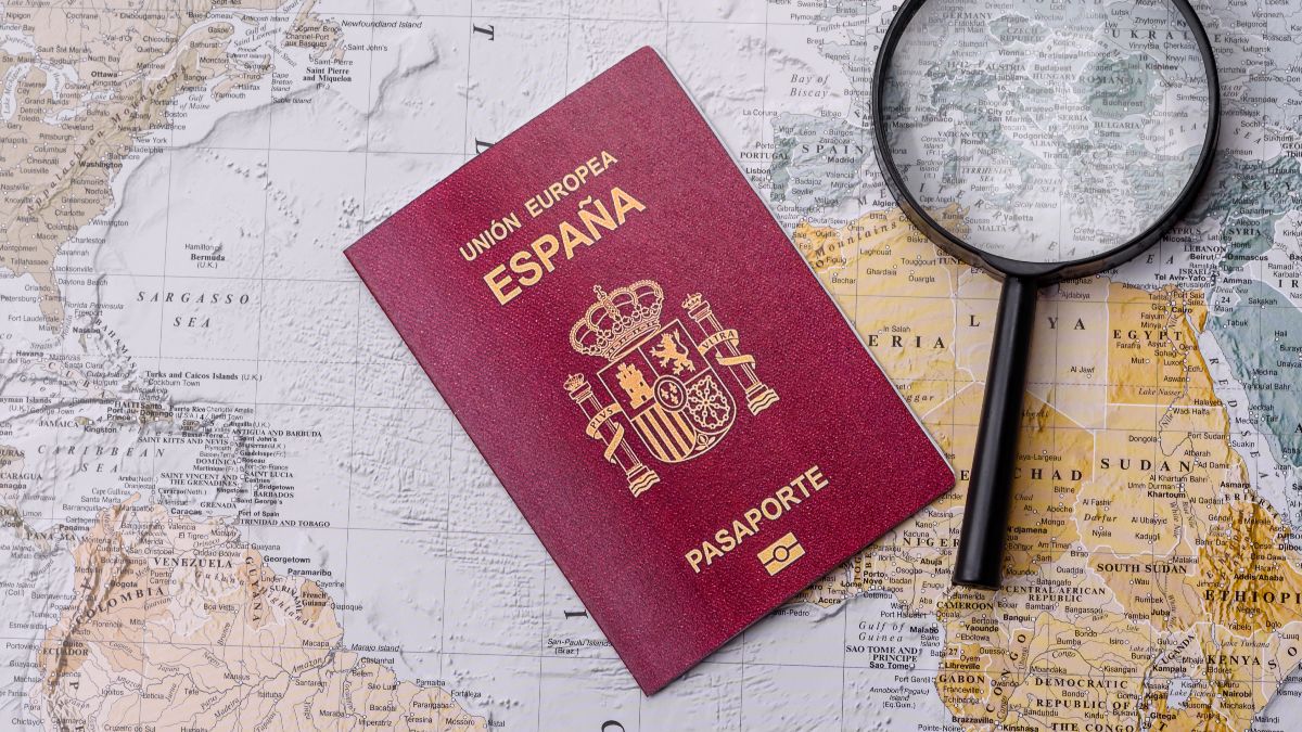 un pasaporte español sobre el mapa del mundo y una lupa