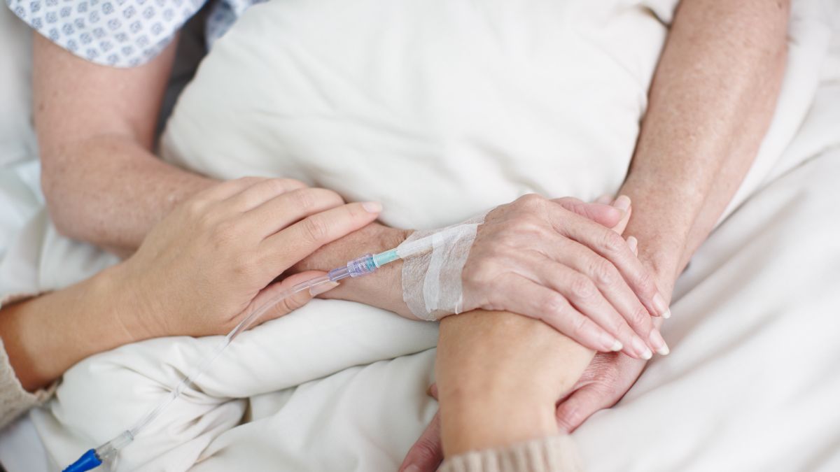 Una persona sujetando la mano a otra persona enferma