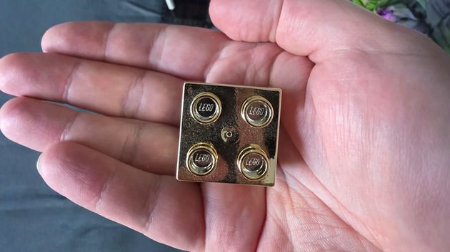 Un empleado de LEGO muestra lo que recibió por su cuarto aniversario en la empresa: un ladrillo Lego dorado que ahora todos quieren tener