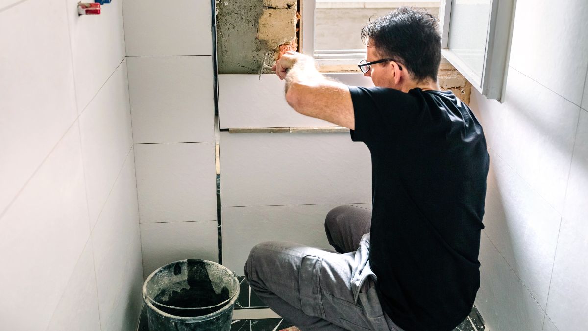 Un hombre reparando los azulejos de un baño