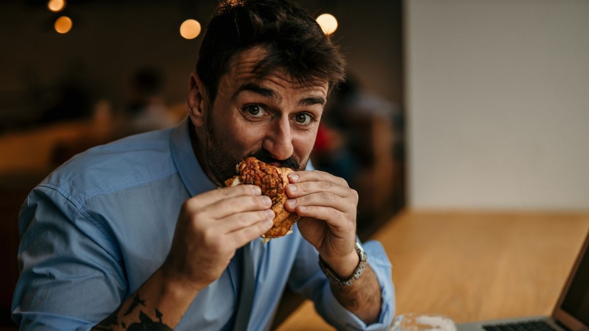 Una persona come una empanada de pollo en su puesto de trabajo