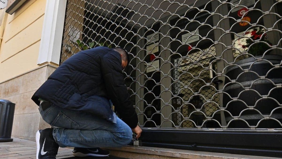 Un trabajador echando la persiana a su negocio