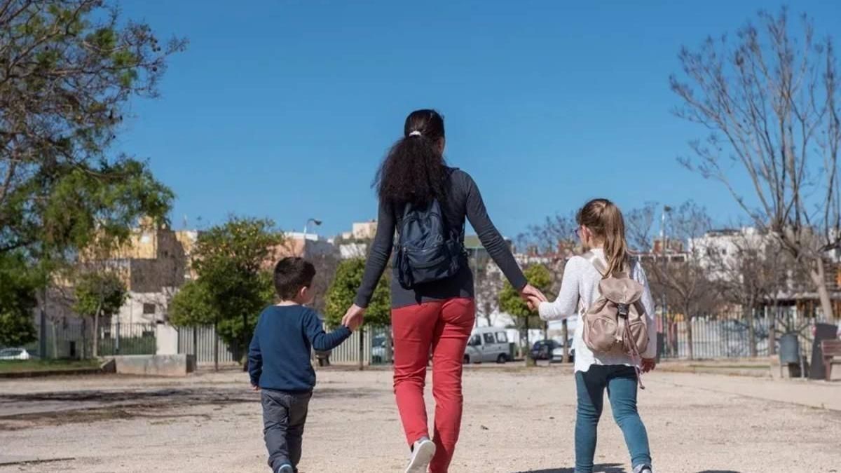 Una mujer pasea con dos niños de la mano