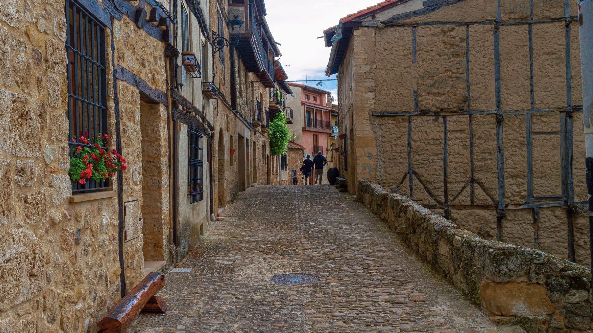 Una pareja pasea de la mano por unas calles empedradas