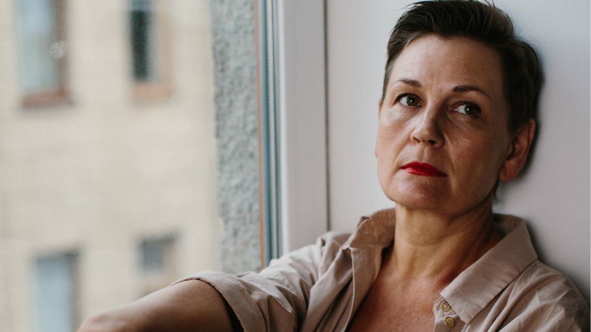 Una mujer triste apoyada en la ventana