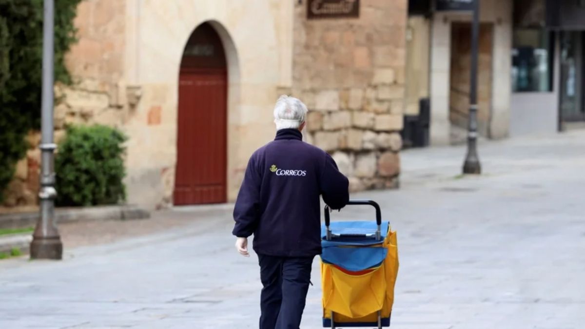 Una trabajadora mayor de Correos camina por una calle