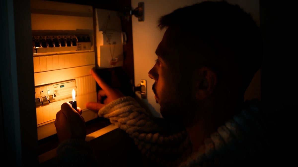 un hombre con un mechero delante del contador de electricidad