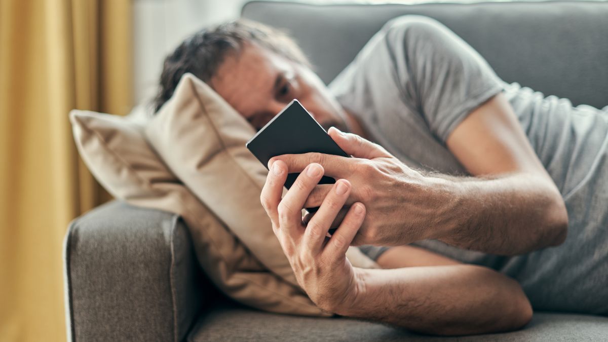 Un hombre en el sofá mirando el móvil