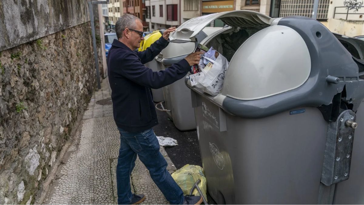 Un hombre tirando una bolsa de basura al contenedor