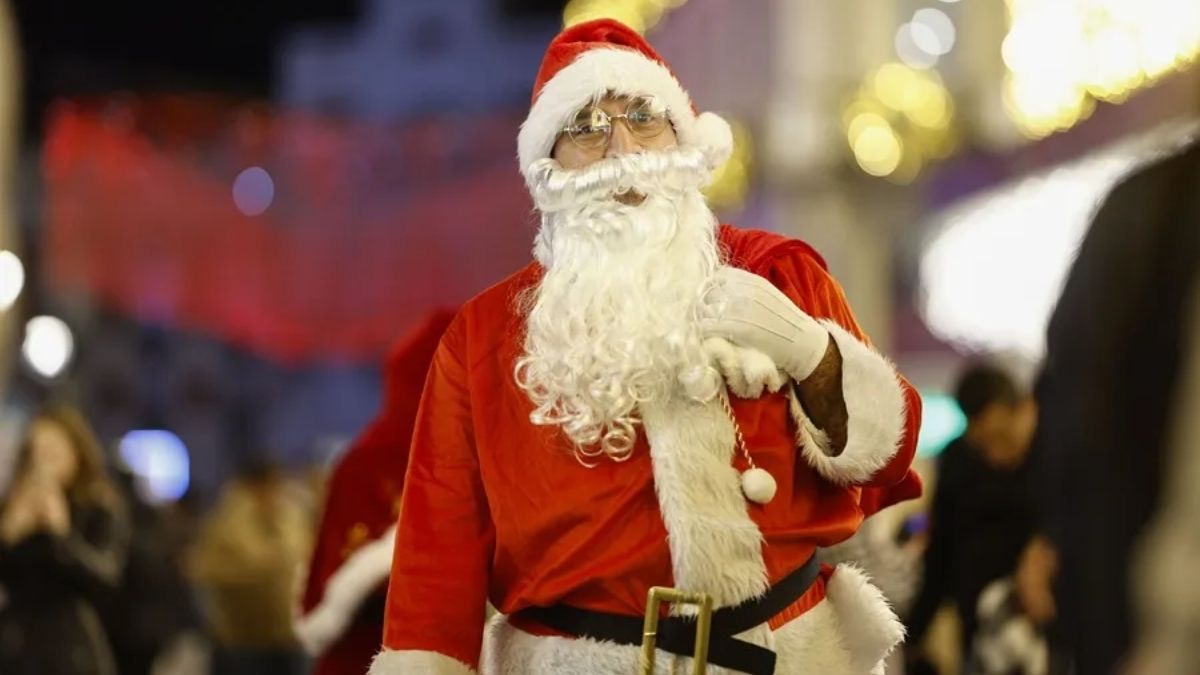 Un papá noel caminando con un saco en medio de la calle