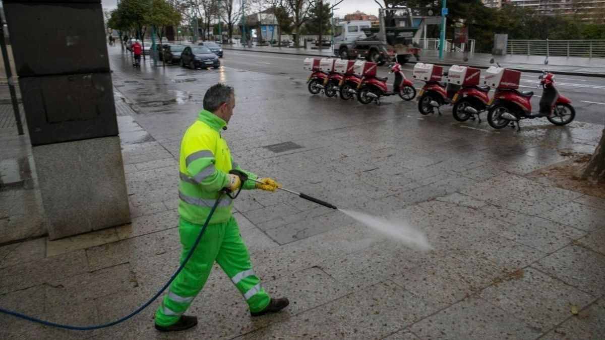 Un trabajador de la limpieza echando agua en la calle