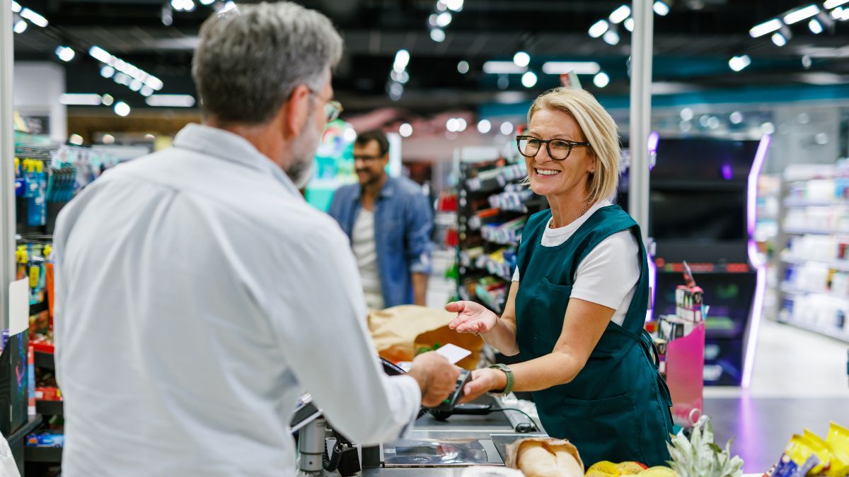 Una cajera de supermercado atiende a un cliente. 