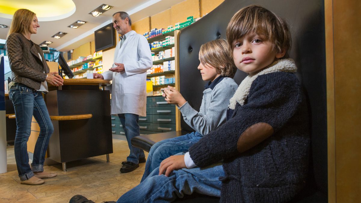 Unos niños esperando a su madre en la farmacia