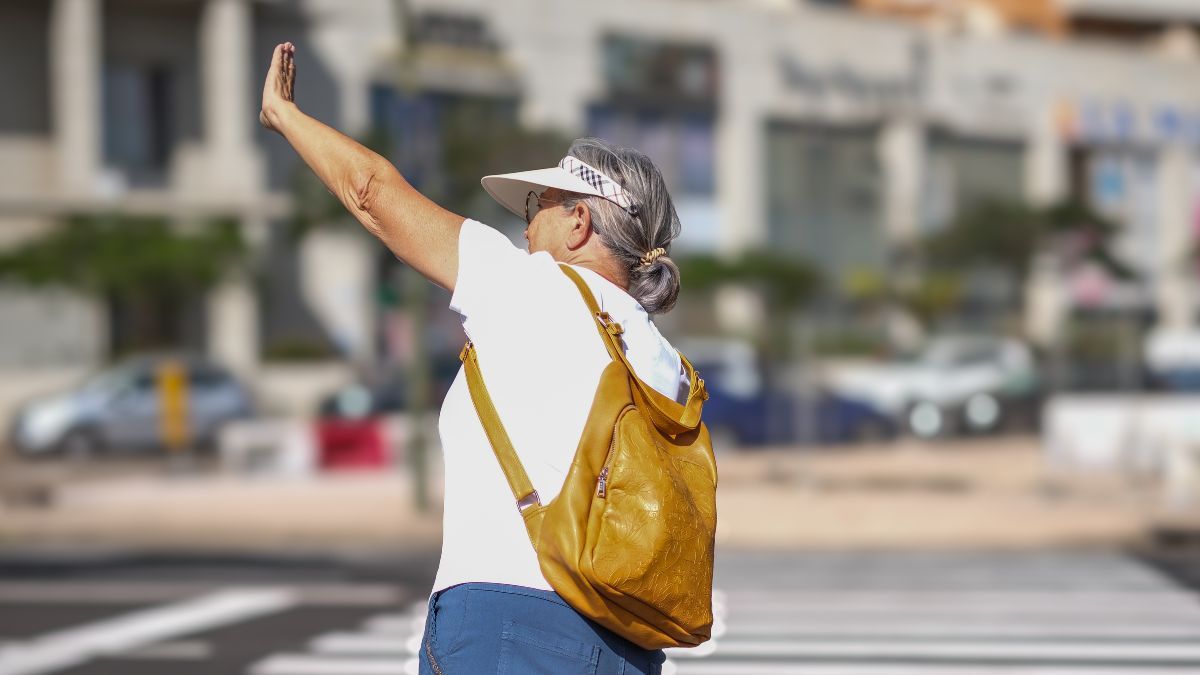 Una mujer saluda al cruzar el paso de peatones