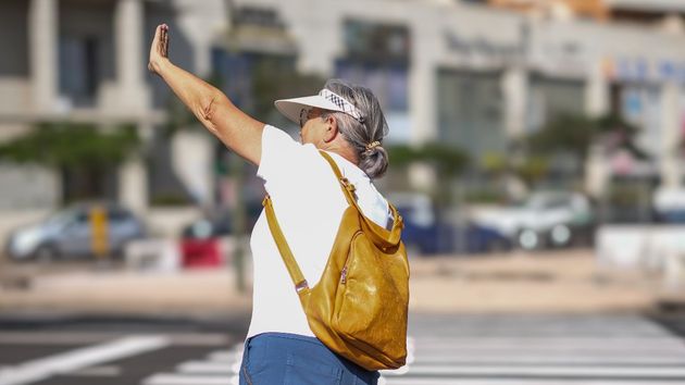 Una mujer saluda al cruzar el paso de peatones