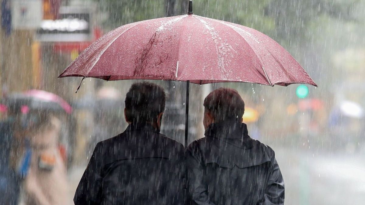 Unos paseantes se protegen con un paraguas