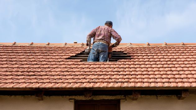 Un hombre reparando el tejado de una casa