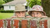 Una pareja de jubilados espiando tras un muro