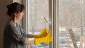 Una empleada de hogar limpiando la ventana