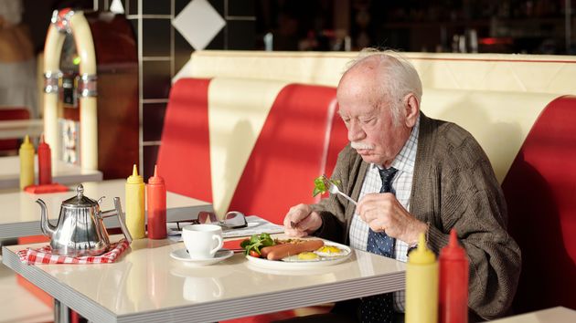 un anciano comiendo en un restaurante