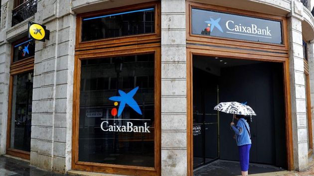 Una mujer frente a una oficina de CaixaBank