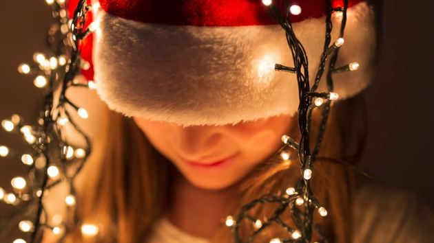 joven con gorro y luces de Navidad sobre la cabeza