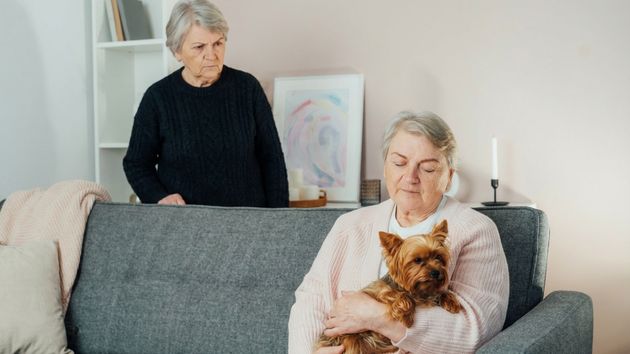 Un mujer mirando mal a otra que sostiene un perro