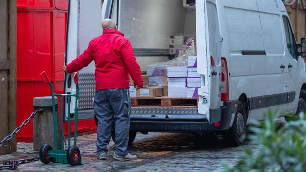 un trabajador mayor de 55 años con una furgoneta y paquetes de envío