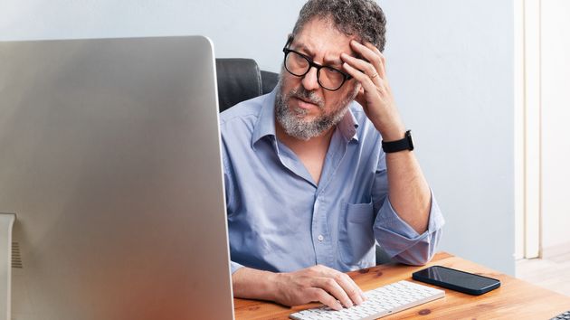 Un hombre con rostro serio frente al ordenador