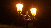 unas farolas encendidas en la calle con nieve