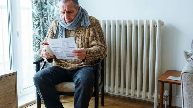 Un hombre con frio revisando la factura de calefacción