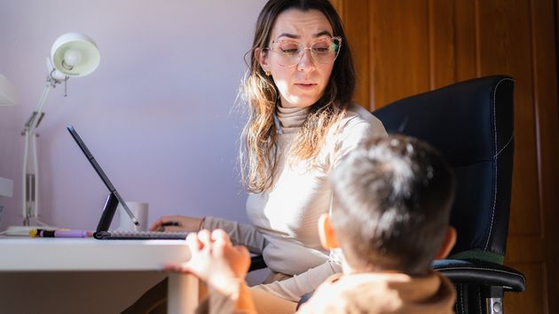 Una madre teletrabajando con su hijo pequeño