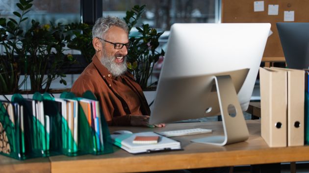 Un trabajador en frente de su ordenador, con actitud jocosa