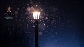Una farola encendida con nieve cayendo