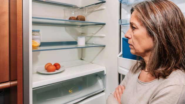 Una mujer mirando un frigorífico casi vacío