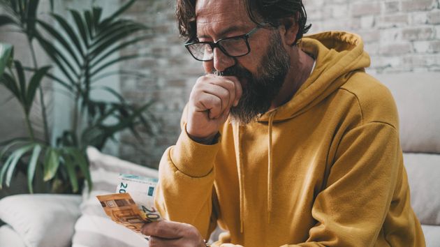 Un hombre pensativo con dinero en la mano