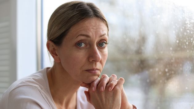 Una mujer triste junto a una ventana