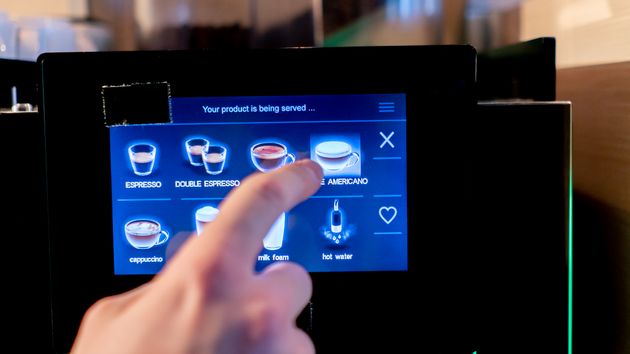 Una persona seleccionando un café en una máquina