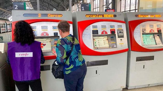 Una empleada de Renfe ayuda a otra mujer a sacar un billete