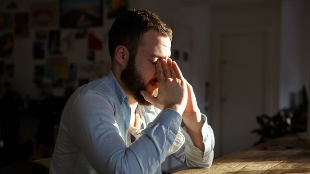 Un hombre cabizbajo tapándose la cara